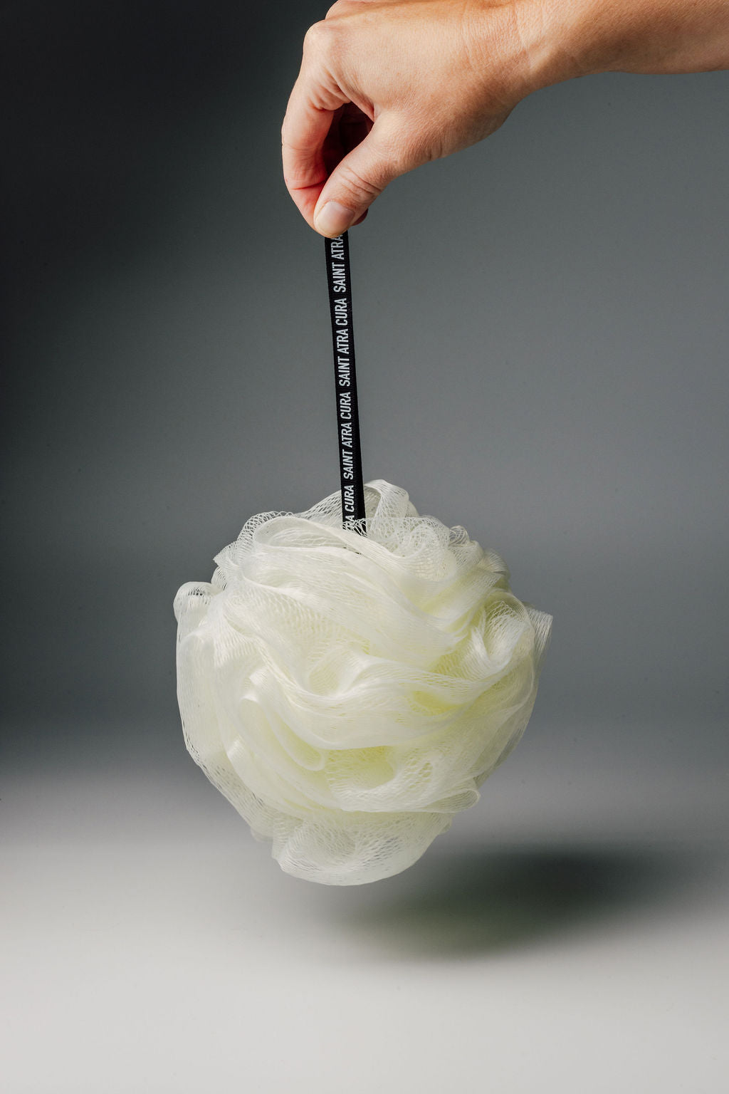 White bath pouf. Luxury Loofah by Saint Atra Cura.  Black branded handle. Skincare, shower loofah, perfect gift