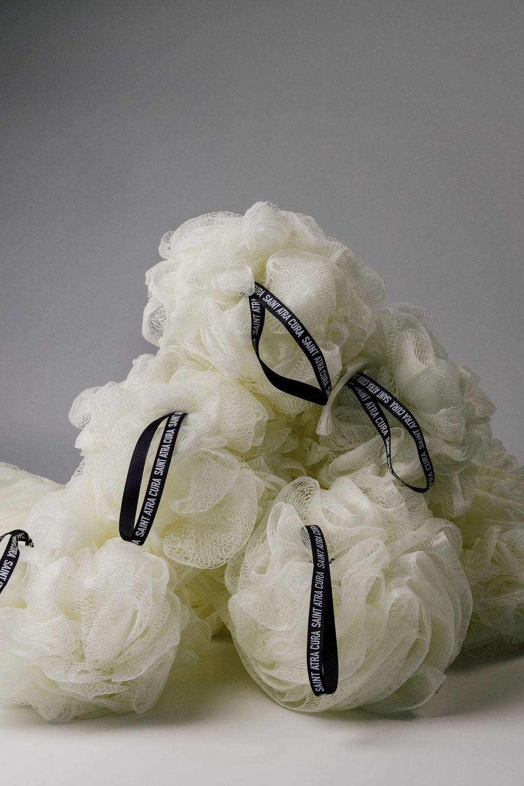 White bath pouf. Luxury Loofah by Saint Atra Cura.  Black branded handle. Skincare, shower loofah, perfect gift